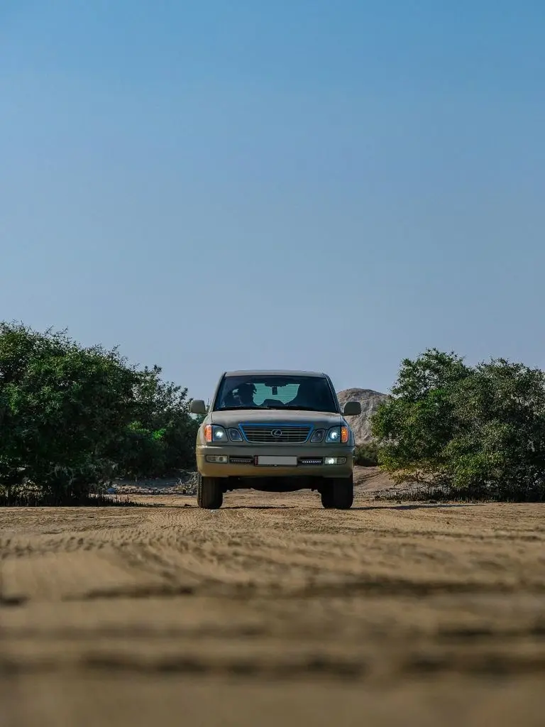 An overland vehicle with a closed Kuafo tent heading down a dirt road at sunset